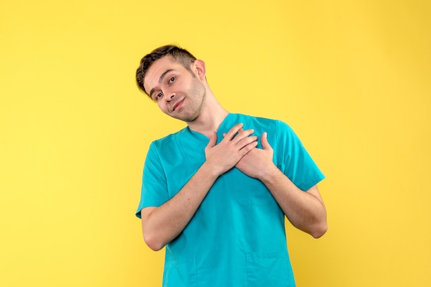 Vue de face du médecin de sexe masculin souriant sur mur jaune