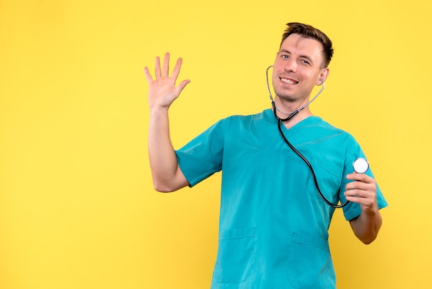 Vue de face du médecin de sexe masculin souriant avec tonomètre sur mur jaune