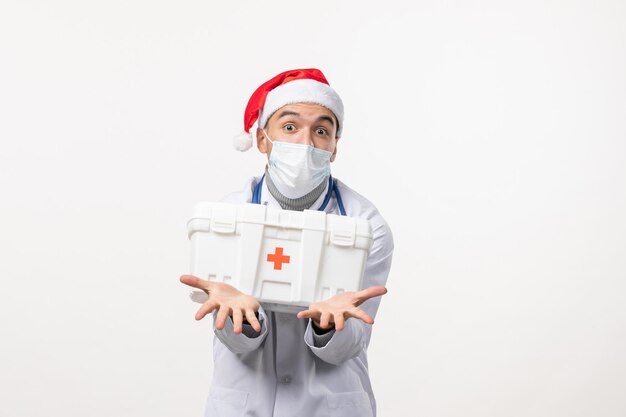 Vue de face du médecin de sexe masculin avec trousse de premiers soins sur mur blanc