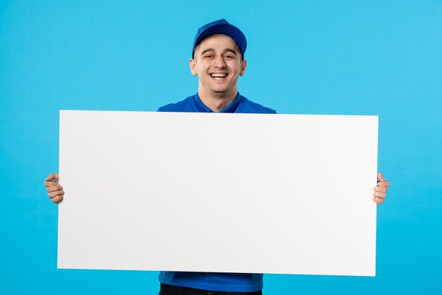 Vue de face du messager masculin en uniforme bleu avec un bureau uni blanc sur bleu