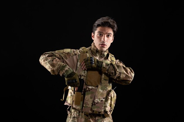 Vue de face du militaire en uniforme sur mur noir