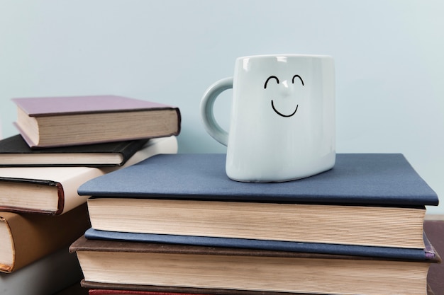 Photo gratuite vue de face du mug heureux sur les livres avec un fond uni