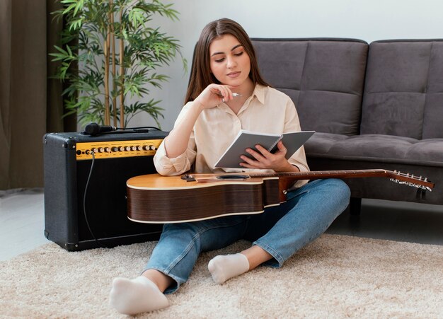 Vue de face du musicien féminin avec guitare acoustique, écriture de chansons