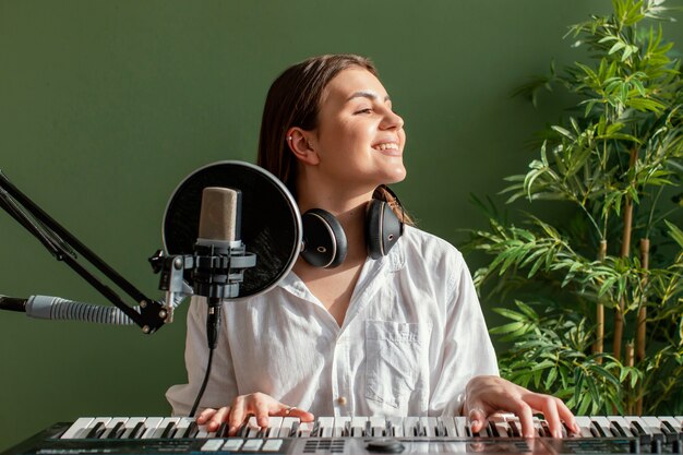 Vue de face du musicien féminin smiley jouant du clavier de piano à l'intérieur