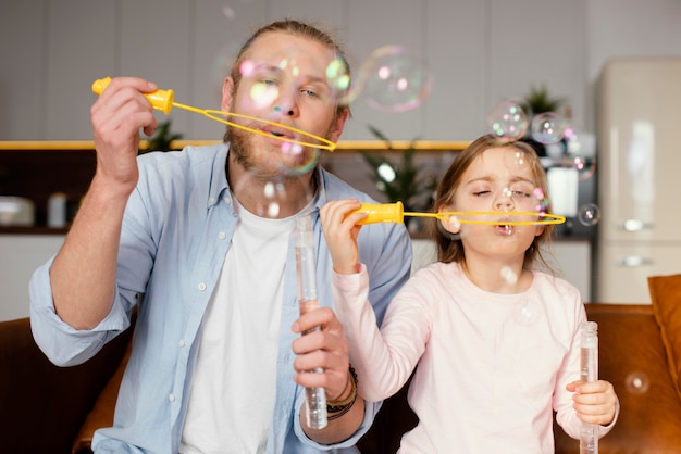 Photo gratuite vue de face du père et de la fille jouant avec des bulles de savon