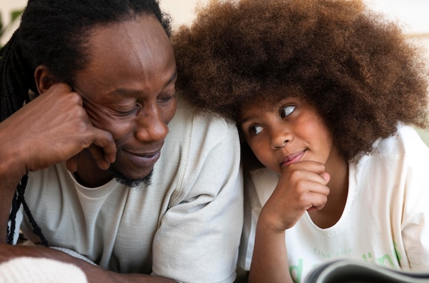 Vue de face du père et de la fille lisant un livre ensemble