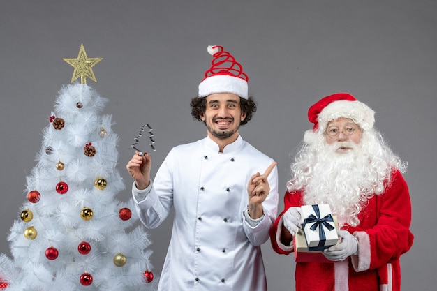 Vue de face du père noël autour de l'arbre de vacances avec un cuisinier masculin