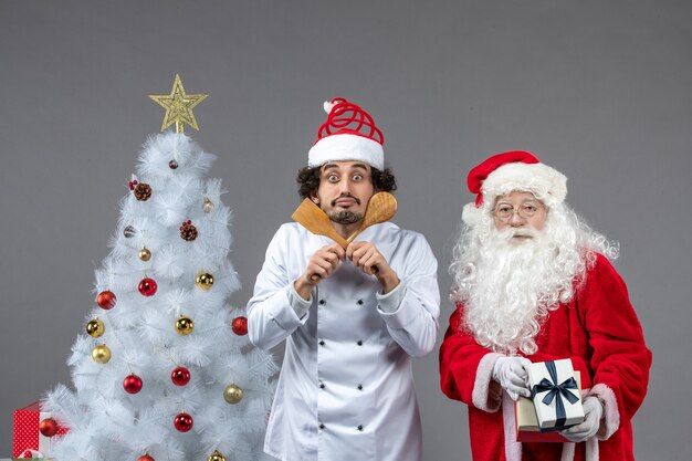 Vue de face du père noël autour de l'arbre de vacances avec un cuisinier masculin