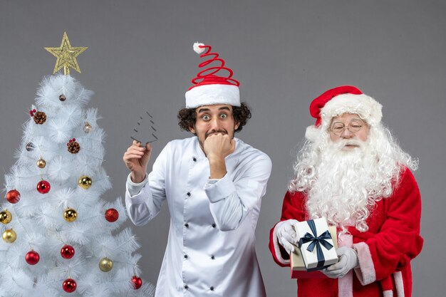 Vue de face du père noël autour de l'arbre de vacances avec un cuisinier masculin