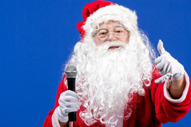 Vue de face du père noël avec un costume rouge et une barbe blanche tenant un micro sur un sol bleu vacances noël nouvel an neige