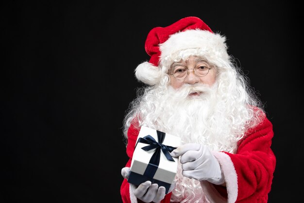 Vue de face du père noël en costume rouge classique tenant un cadeau