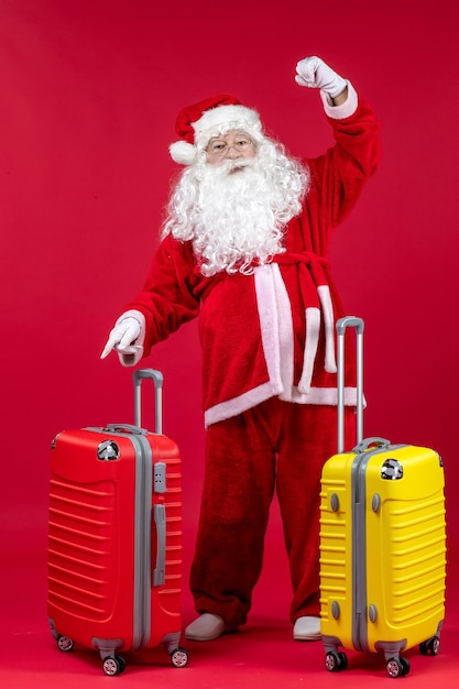 Vue de face du père Noël avec deux sacs se préparant pour le voyage sur le mur rouge