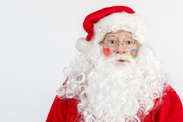 Vue de face du père Noël avec drapeau azerbaïdjanais et turc peint sur son visage sur mur blanc