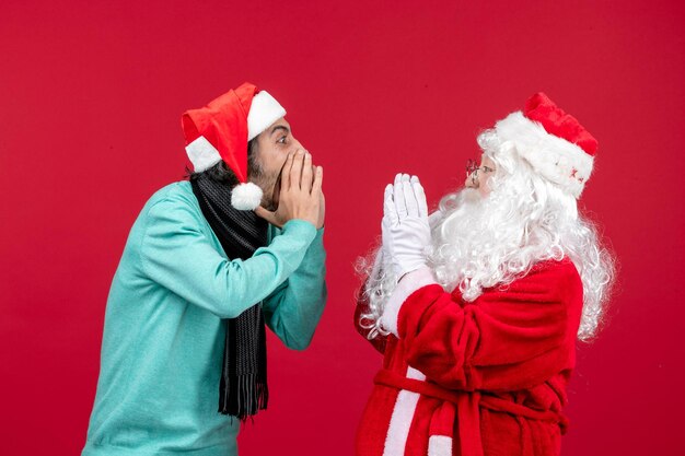 Vue de face du père noël avec des hommes interagissant les uns avec les autres sur le cadeau de noël rouge