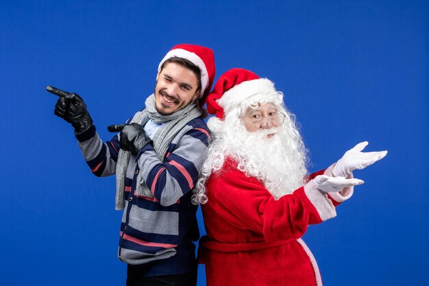 Vue de face du père noël avec un jeune homme sur le mur bleu