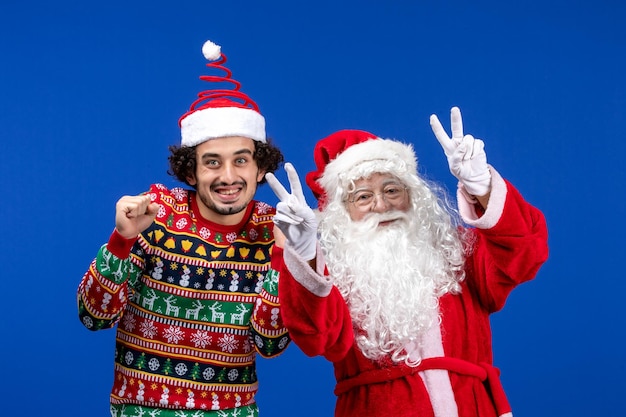 Vue de face du père noël avec un jeune homme sur le mur bleu