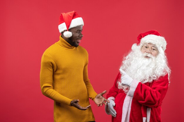 Vue de face du père Noël avec jeune homme sur mur rouge