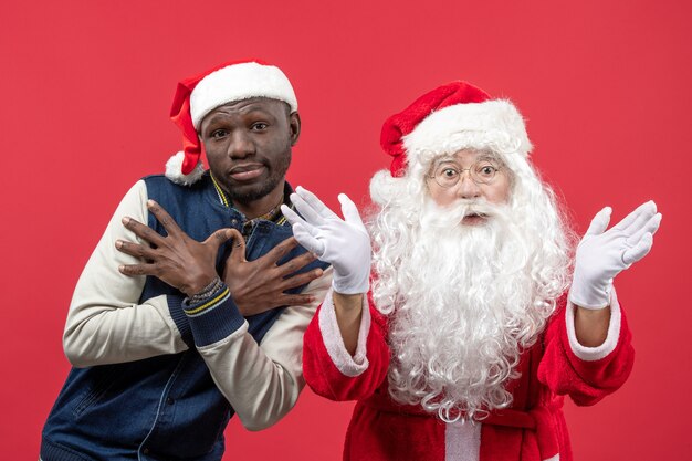 Vue de face du père Noël avec jeune homme sur mur rouge