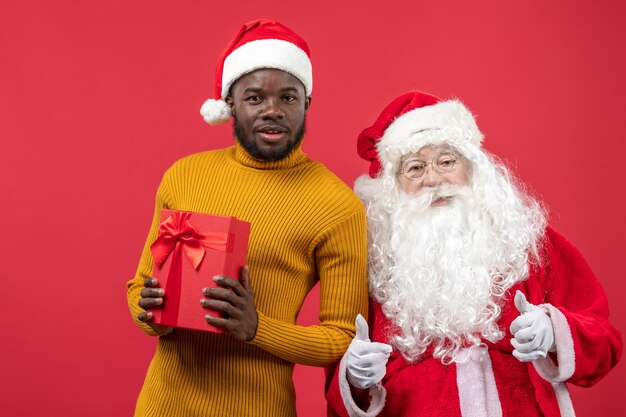 Vue de face du père Noël avec jeune homme sur mur rouge