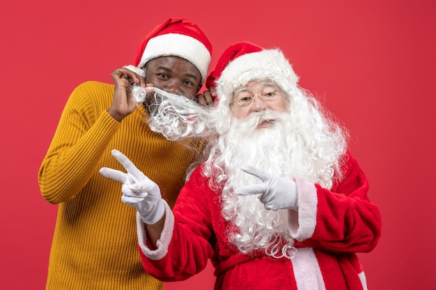 Vue de face du père Noël avec jeune homme sur mur rouge