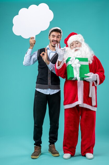 Vue de face du père Noël avec jeune homme qui tient un signe de nuage blanc sur fond bleu