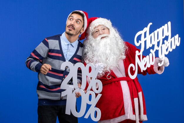 Vue de face du père noël avec un jeune homme tenant une bonne année et des écrits en pourcentage sur le mur bleu