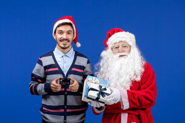 Vue de face du père Noël avec jeune homme tenant des cadeaux