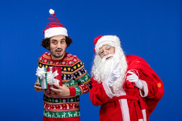 Vue de face du père Noël avec jeune homme tenant des cadeaux