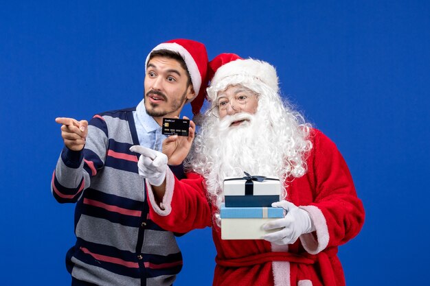 Vue de face du père Noël avec jeune homme tenant des cadeaux