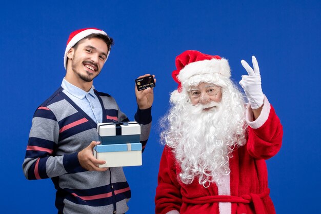 Vue de face du père Noël avec jeune homme tenant des cadeaux