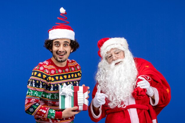 Vue de face du père Noël avec jeune homme tenant des cadeaux