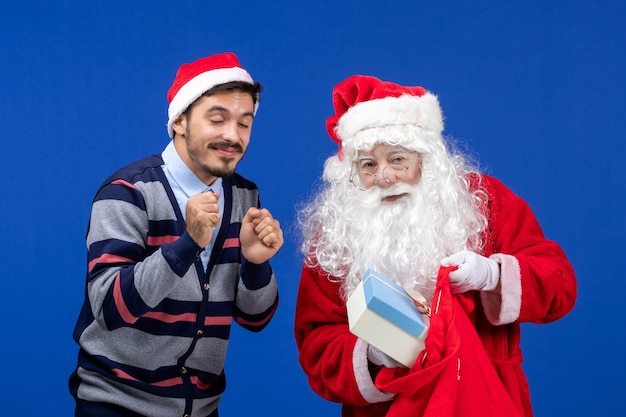 Vue de face du père Noël avec jeune homme tenant un sac de cadeaux