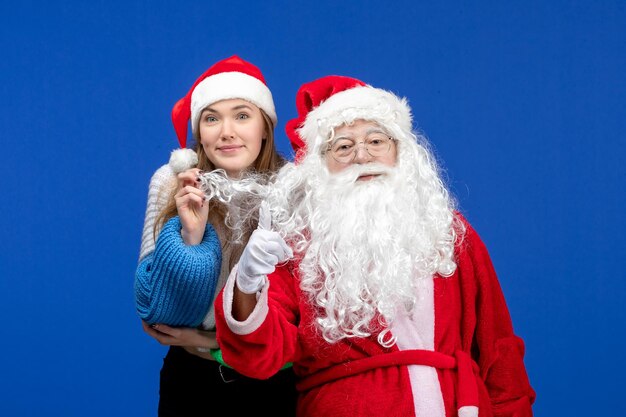 Vue de face du père noël avec une jeune jolie femme sur le mur bleu