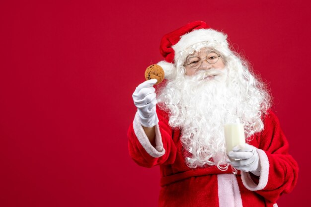 Vue de face du père noël mangeant des biscuits et buvant du lait