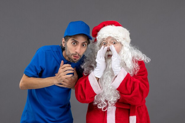 Photo gratuite vue de face du père noël avec messager masculin sur le mur gris