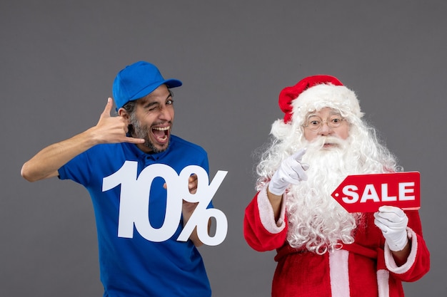 Vue de face du père Noël avec messager masculin tenant des bannières de vente sur un mur gris