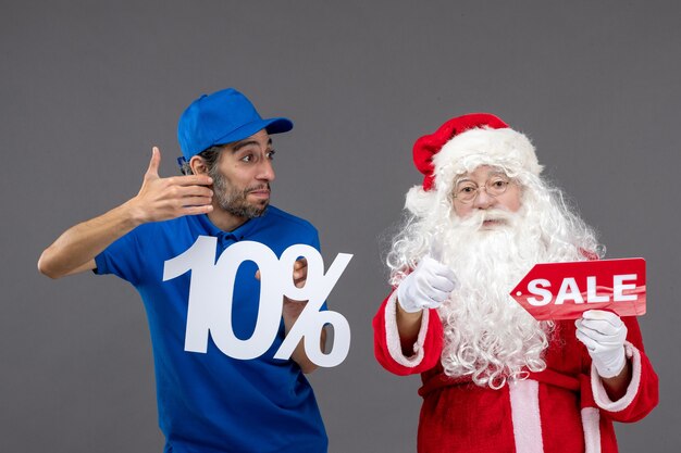 Vue de face du père Noël avec messager masculin tenant des bannières de vente sur un mur gris