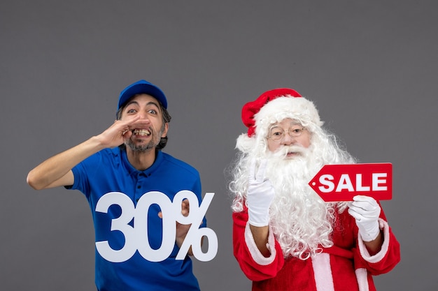 Vue de face du père Noël avec messager masculin tenant des bannières de vente sur un mur gris