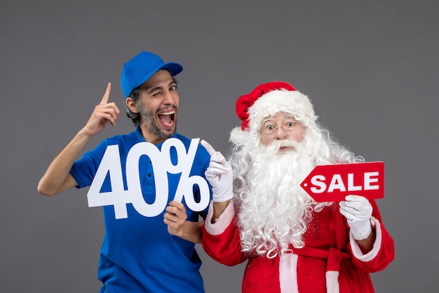 Vue de face du père Noël avec messager masculin tenant des bannières de vente sur le mur gris