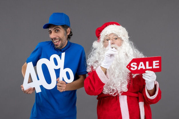 Vue de face du père Noël avec messager masculin tenant des bannières de vente sur le mur gris