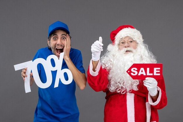 Vue de face du père Noël avec messager masculin tenant des bannières de vente sur le mur gris