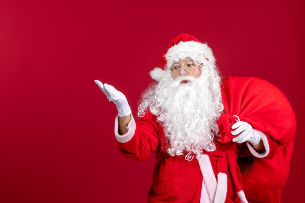 Vue de face du père noël portant un sac rouge plein de cadeaux sur l'émotion rouge des vacances de noël du nouvel an