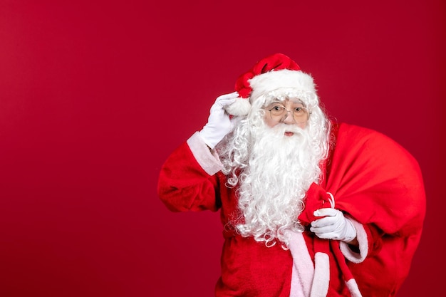 Vue de face du père noël portant un sac rouge plein de cadeaux sur les vacances de nouvel an de l'émotion de noël rouge