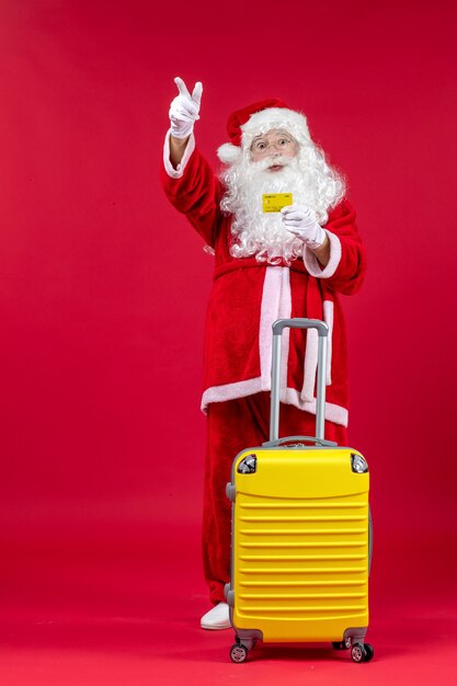 Vue de face du père Noël avec sac jaune tenant une carte bancaire jaune sur le mur rouge