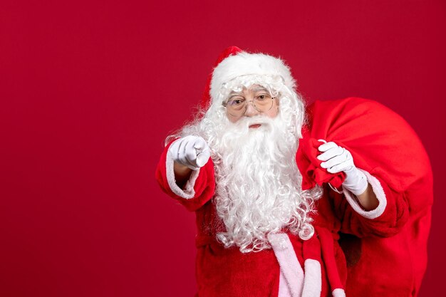 Vue de face du père noël avec un sac plein de cadeaux sur un bureau rouge vacances nouvel an émotion de noël