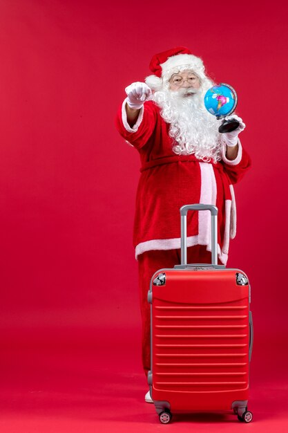 Vue de face du père Noël avec sac de préparation pour le voyage sur le mur rouge