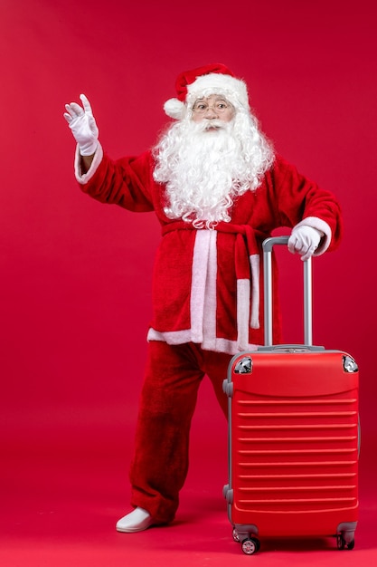 Vue de face du père Noël avec son sac rouge sur le mur rouge