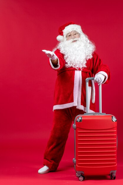 Vue de face du père Noël avec son sac rouge sur le mur rouge