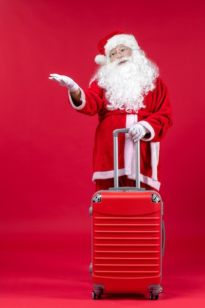 Vue de face du père Noël avec son sac rouge sur le mur rouge