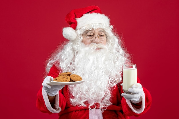 Vue de face du père noël tenant des biscuits et un verre de lait